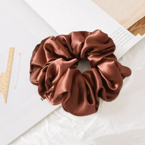 Detail of silk satin brown scrunchie showing smooth texture and soft glossy fabric