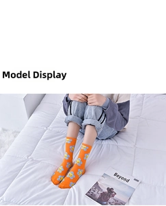 Detail of vibrant orange crew socks featuring blue smiling floral patterns on a white bed