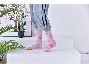 Close-up of purple mid-calf cotton socks featuring yellow smiley faces and pink flowers