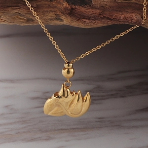 Detailed close-up of a golden seashell pendant necklace on a rustic wooden background
