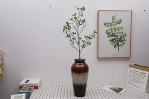 Modern ceramic vase with artificial Milan leaves on a black and white checkered cloth
