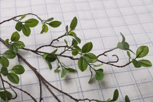 Macro view of artificial Milan leaves with green foliage and brown textured branches