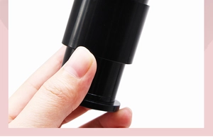 Detail shot of the portable black retractable makeup brush handle in a hand with white background