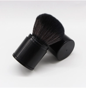 Detail of a portable retractable black makeup brush with lid and soft synthetic bristles