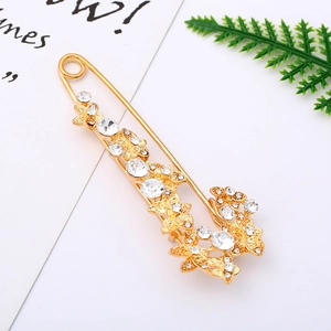 Detail of a gold alloy safety pin brooch featuring crystal flowers and butterfly accents