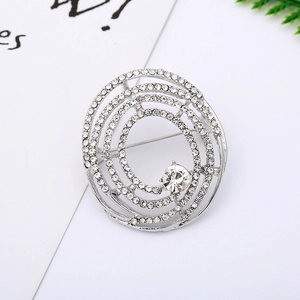 Detail of spiral brooch with white rhinestones and a central crystal on white background
