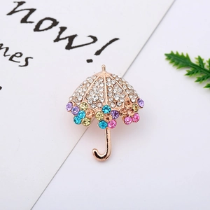Detailed view of an umbrella brooch featuring colorful crystals on a gold metal base