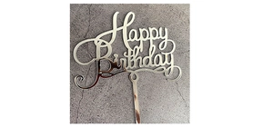 Close-up of a silver mirror acrylic Happy Birthday cake topper on a grey surface