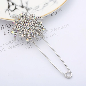 Vintage silver sunflower brooch with rainbow AB rhinestones on marble background