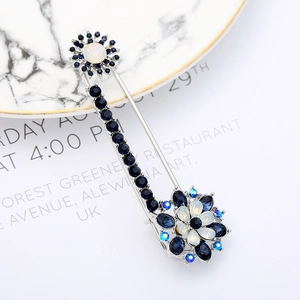Detail of silver vintage floral brooch with blue and white crystals on marble plate