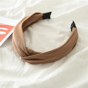 Detail shot of a brown fabric knotted headband on a soft white draped cloth background
