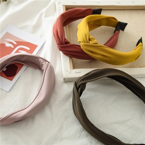 Flat lay of four knotted fabric headbands in pink, rust red, yellow, and dark brown