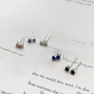 Close-up of five S925 silver stud earrings with multi-color zircon stones on book background