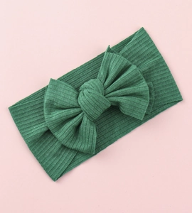 Macro detail of dark green ribbed knit baby headband with a large decorative bow