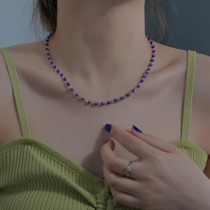 Harajuku evil eye beaded necklace with gold base and a minimalist diamond ring on model