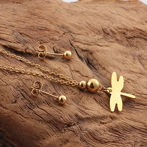 Elegant 18K gold dragonfly pendant necklace and ball stud earrings set on wood base