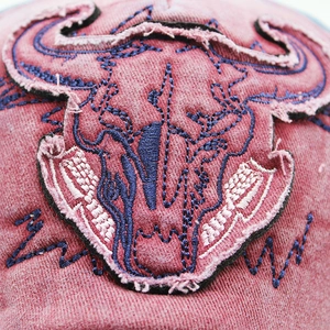 Macro view showing bull skull embroidery and vintage washed denim texture on baseball cap