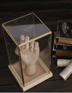 Detail of a glass display box with golden metal edges and light wood base stand