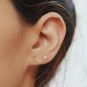 Macro detail of crescent moon and star stud earrings with sparkling crystals on ear