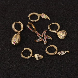 Detailed close-up of golden sea-themed earrings with colorful zircons on black background