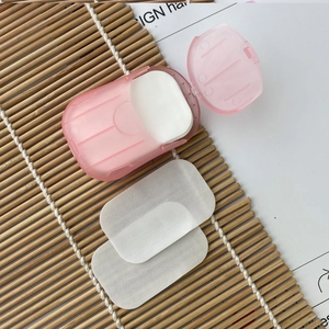 Portable pink soap paper case with white disposable flakes on a minimalist bamboo mat