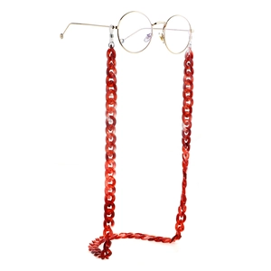 Red acrylic glasses chain with large links and gold round frame spectacles on white background