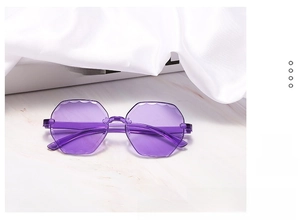 Detail view of purple rimless sunglasses with wavy scallop edges on a marble surface