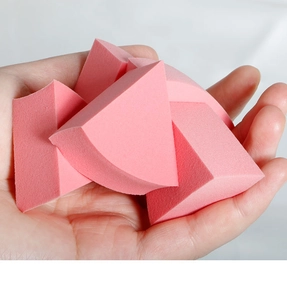 Close-up of soft pink triangular makeup sponges held in hand for size and texture detail