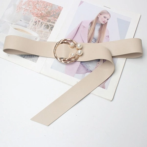 Détail d'une ceinture beige à boucle perlée sur un magazine de mode avec un éclairage doux