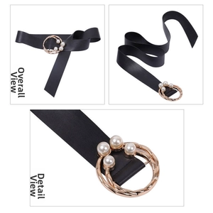 Détail de la ceinture en cuir noir avec boucle dorée ronde et trois perles blanches