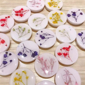 Flat lay view of multiple round resin phone grips with colorful dried flowers on wood