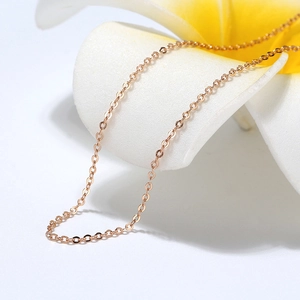 Close-up of a delicate rose gold cable chain necklace draped over a frangipani flower