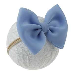 Détail d'un bandeau bébé avec un grand nœud bleu ciel et une texture de tissu fine