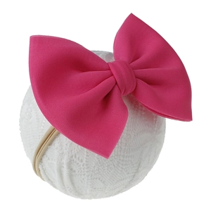 Détail d'un bandeau à gros nœud rose tricoté avec élastique souple pour bébés
