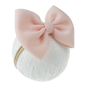 Vue détaillée d'un bandeau rose avec nœud pour bébé sur support en dentelle, tissu doux