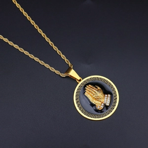 Detail of gold hip hop pendant with praying hands relief and Greek key edge