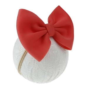 Vue détaillée d'un bandeau à gros nœud rouge pour bébé sur une sphère en dentelle.
