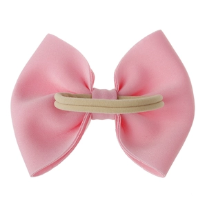 Vue détaillée d'un grand nœud en tissu rose avec un bandeau en nylon beige doux