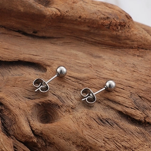Boucles d'oreilles boules classiques en acier inoxydable argenté sur surface en bois