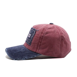 Close-up of distressed brim and patch embroidery on vintage red and blue baseball cap