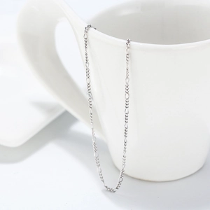 Detailed view of s925 sterling silver 1.7mm Figaro chain draped over a white ceramic cup