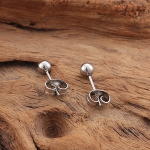 Minimalist silver stud earrings with round bead design on a rustic wooden surface