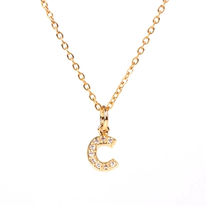 Macro detail of gold initial C pendant necklace with sparkling cubic zirconia pavé setting