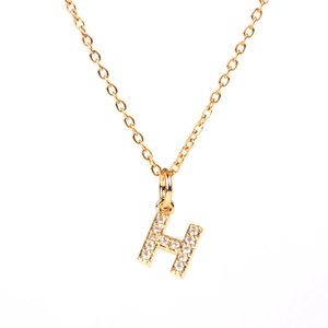 Detailed close-up of a golden H-letter pendant necklace featuring paved zircon stones
