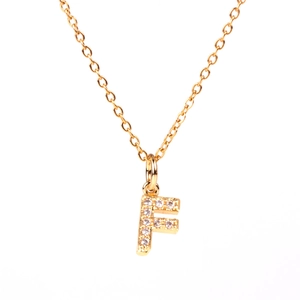 Macro shot of gold letter F pendant with sparkling white cubic zirconia on chain