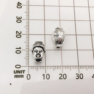 Macro detail of silver Buddha-shaped alloy beads with dimensions on a metric scale