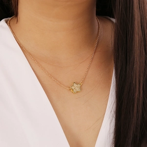 Close-up of gold star pendant with small crystals worn on a delicate O-link chain