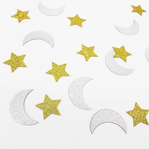 Macro shot of gold star and silver moon confetti with glitter texture on white background