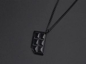 Macro shot of a black bitten chocolate bar pendant on a sleek titanium steel chain