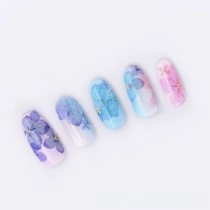 Macro shot of 3D gradient hydrangea nail decals with gold sequins and floral patterns